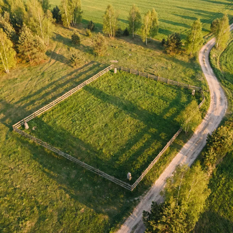 Widok z drona — ogrodzona pusta działka budowlana w polskim krajobrazie