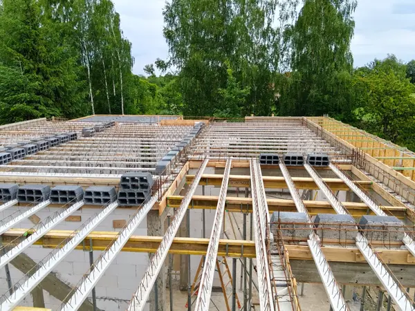 Strop typu Teriva z góry — pustaki, belki kratownicowe, zbrojenie wieńców przed zalaniem betonem, fragment budowy domu jednorodzinnego
